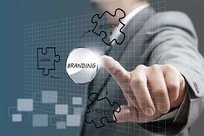 انگشت در حال لمس دکمه BRANDING میان قطعات پازل Mission و Vision، طراحی لوگو