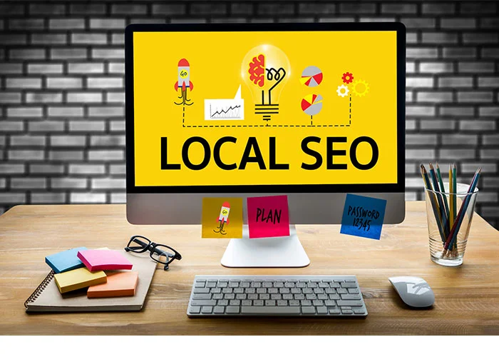 مانیتور با عبارت LOCAL SEO روی میز کار با یادداشت‌های رنگی